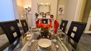 a glass table with red flowers in a living room at Stunning Holiday Home. Free Parking. in Manchester