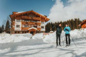 拉姆绍达赫斯坦林德霍夫酒店的两人在小屋前的雪地滑雪