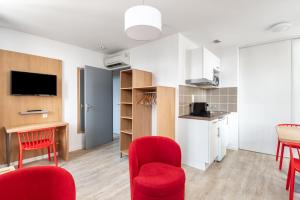 sala de estar con sillas rojas y cocina en Residhotel Le Central'Gare, en Grenoble