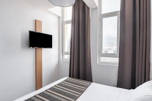 1 dormitorio con 1 cama, TV y 2 ventanas en Residhotel Le Central'Gare, en Grenoble