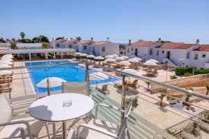 een balkon met tafels en parasols en een zwembad bij Naranjos Resort Menorca in S'Algar