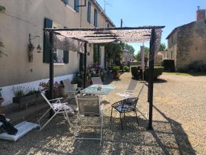 een patio met een tafel en stoelen onder een pergola bij La Revaudiere in Bressuire