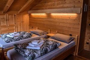 two beds in a room with wooden walls at Appartamento Mainardi in Auronzo di Cadore