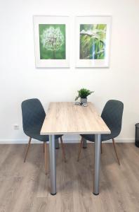 een eettafel met twee stoelen en twee foto's aan de muur bij greenpartment Boardinghousehotel Kelheim in Kelheim