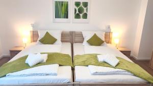 een slaapkamer met 2 bedden met groene en witte kussens bij greenpartment Boardinghousehotel Kelheim in Kelheim