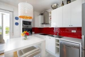 a kitchen with white cabinets and red walls at Marina Lux Split in Split