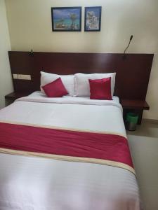 een slaapkamer met een groot bed met 2 rode kussens bij BLUEWAY RESIDENCY BUSINESS BOUTIQUE HOTEL in Trivandrum