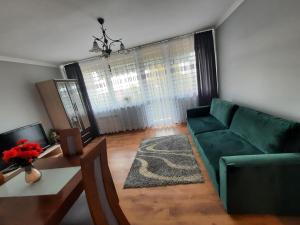 uma sala de estar com um sofá verde e uma mesa em Słoneczny Apartament w Busku-Zdroju em Busko-Zdrój