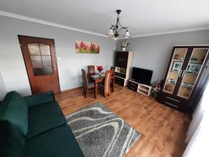 uma sala de estar com um sofá verde e uma mesa em Słoneczny Apartament w Busku-Zdroju em Busko-Zdrój