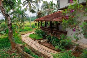 a garden with a small building and a walkway at Wayal Wayanad Heritage villa in Panamaram