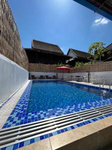 - une piscine avec des carreaux bleus sur le côté d'un bâtiment dans l'établissement Little Friendly Guest House and Swimming Pool, à Luang Prabang