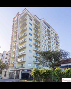 a tall white building with a tree in front of it at Meshaal heights in Mombasa