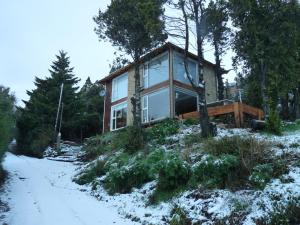 une maison dans les bois dans la neige dans l'établissement Apartments Seeblick Bariloche, à San Carlos de Bariloche