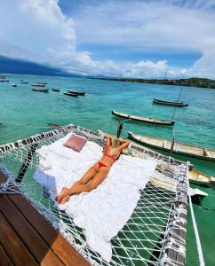 uma mulher deitada numa cama num barco na água em Indigo Blue Ceningan em Nusa Lembongan