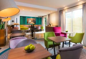 un restaurante con mesas y sillas coloridas en Hotel Acanthe - Boulogne Billancourt, en Boulogne-Billancourt