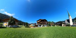 un pequeño pueblo con una iglesia y un campo verde en Hotel Alpenland, en Niederau