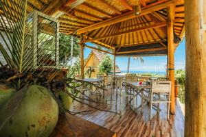 um pavilhão com mesas e cadeiras num piso de madeira em Atuh Forest Cottage em Nusa Penida