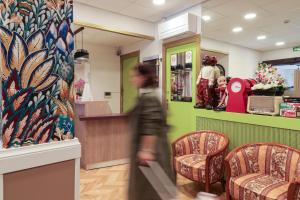 a woman walking through a store lobby with chairs at Hôtel Gloria in Grenoble