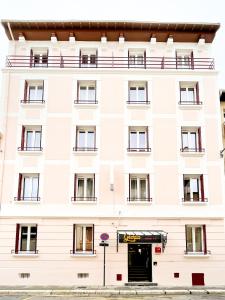 a white building with a door in front of it at Hôtel Gloria in Grenoble