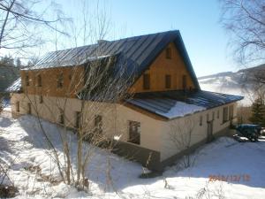 ストラージュネーにあるHotel Vltavaの雪の中の葺き屋根の家