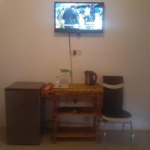 a room with a table and a television on a wall at Sunshinevibe guest house in Kasane