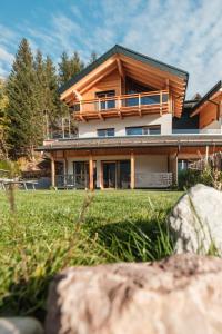 ein Haus mit einem grünen Garten davor in der Unterkunft La Dila Dolomiti Mountain Lodge in Andalo