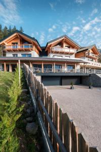 ein großes Haus mit einem Zaun davor in der Unterkunft La Dila Dolomiti Mountain Lodge in Andalo