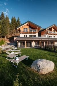 ein Haus mit einem Garten mit Liegestühlen in der Unterkunft La Dila Dolomiti Mountain Lodge in Andalo