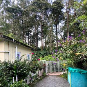 a garden with a white fence and a house at Ammus Homestay in Thekkady