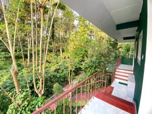 a balcony with a red railing and trees at Ammus Homestay in Thekkady