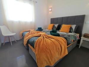 een slaapkamer met 2 bedden met oranje dekens en een stoel bij Apartment 2 bedrooms , centre of Alvor, open view and private parking in Alvor