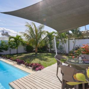 een patio met een tafel en stoelen naast een zwembad bij Villa Primera 3 bedroom bungalow with private pool Grand Bay in Grand Baie