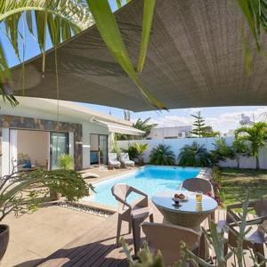 een patio met een zwembad met een tafel en stoelen bij Villa Primera 3 bedroom bungalow with private pool Grand Bay in Grand Baie