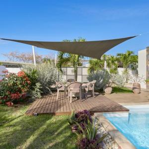 een patio met een tafel en stoelen naast een zwembad bij Villa Primera 3 bedroom bungalow with private pool Grand Bay in Grand Baie