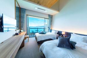 ein Hotelzimmer mit 2 Betten und einem großen Fenster in der Unterkunft Best Western Okinawa Kouki Beach in Nago