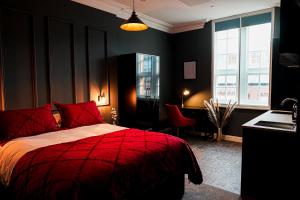 - une chambre noire avec un lit rouge et un bureau dans l'établissement The Old Post Office Warrington by Deuce Hotels, à Warrington