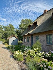 una casa de ladrillo con techo y jardín en Wöda, en Nieblum