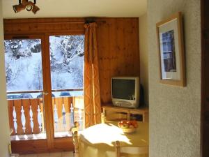 una camera con finestra, TV e tavolo di Appartement de standing au pied des pistes a Morzine