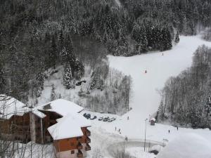 una montagna innevata con un edificio e alberi di Appartement de standing au pied des pistes a Morzine