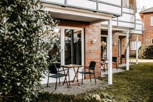 un patio avec des chaises et une table en face d'un bâtiment dans l'établissement Akzent Hotel Zur Grünen Eiche, à Bispingen