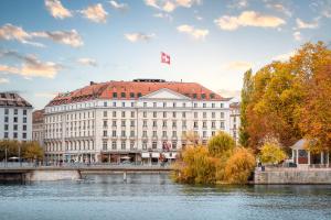 a building with a canadian flag on top of it next to a river at Four Seasons Hotel des Bergues Geneva in Geneva