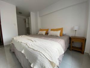 een slaapkamer met een groot wit bed met oranje kussens bij HOMEFULL Apartamentos in Salta