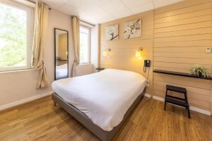 a bedroom with a large white bed and a chair at Le Relais de la Calèche in Le Beausset