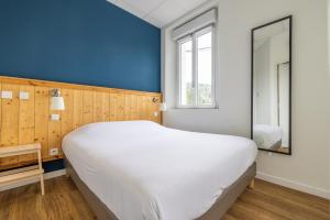 a large white bed in a room with a blue wall at Le Relais de la Calèche in Le Beausset