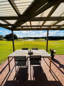 einen Holztisch und Stühle auf einer Terrasse in der Unterkunft Perfect weekend getaway plus golf at your doorstep in Salamander Bay