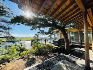 eine Veranda mit einem Baum und Blick auf das Wasser in der Unterkunft Hitachinaka Villa DAN - ひたちなか 暖 - in Hitachinaka