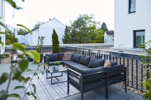 un patio con divano e tavolo sul balcone. di SERVENTO Boardinghouse a Erlangen