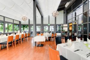 um restaurante com mesas e cadeiras brancas e janelas em Novina Hotel Herzogenaurach Herzo-Base em Herzogenaurach