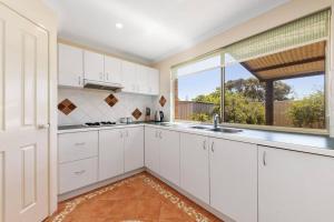 a kitchen with white cabinets and a large window at Light & bright Falcon Bay family holiday escape in Mandurah