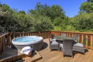 a hot tub on a deck with chairs and a table at South Winchester Lodges in Winchester